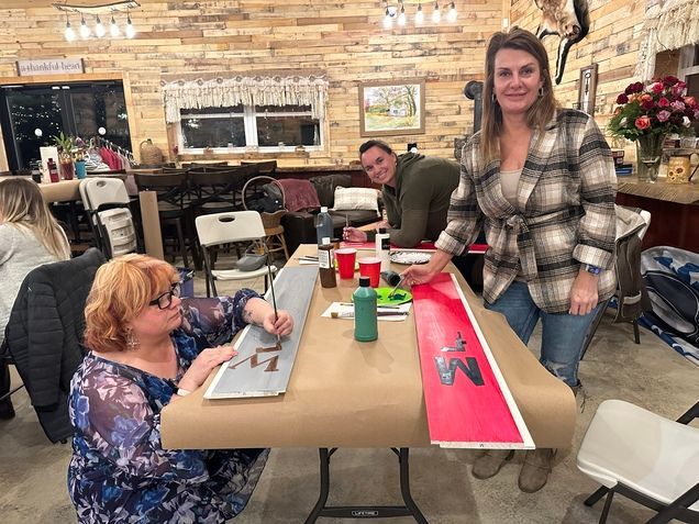 A group of people are sitting at a table painting a picture.