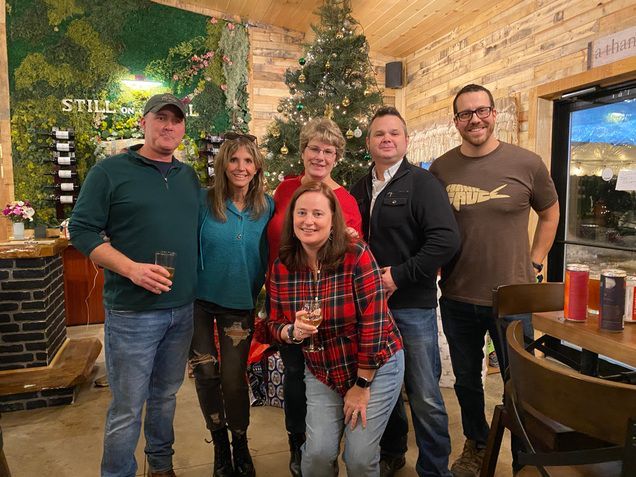 A group of people are posing for a picture in front of a christmas tree.