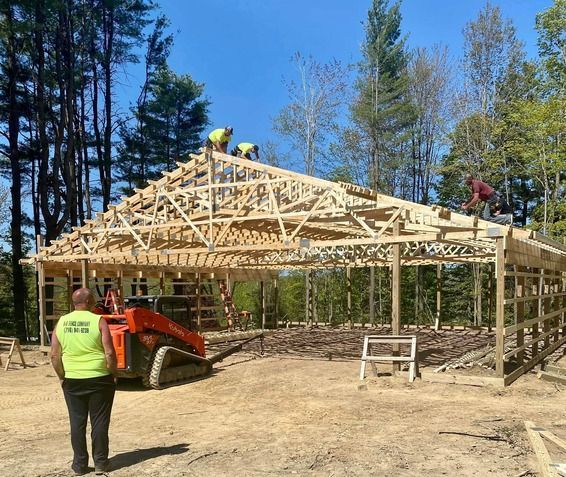A man in a yellow vest is standing in front of a building under construction.