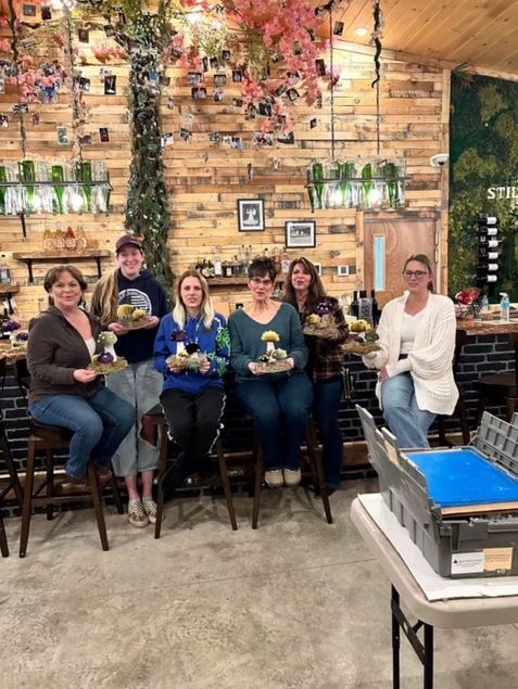A group of people are sitting in a room holding trays of food.