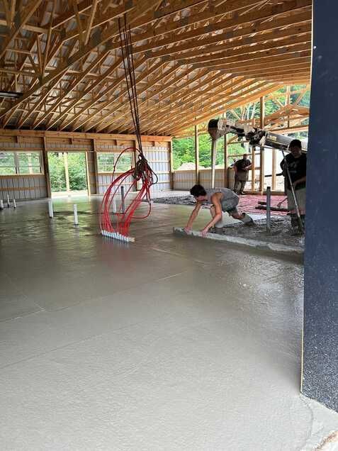 A group of people are working on a concrete floor in a building.