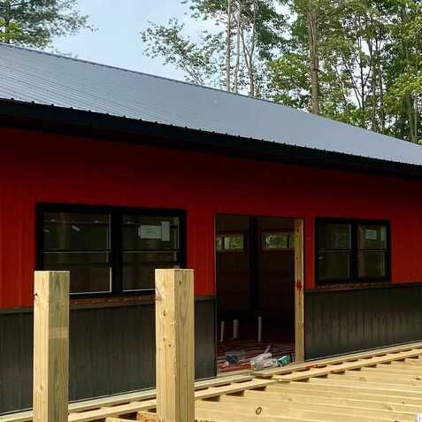 A red building with a black roof and a wooden deck in front of it.