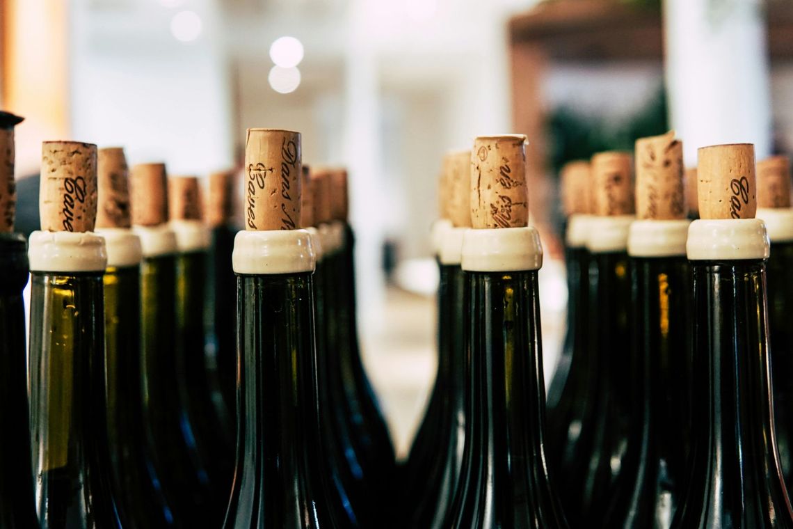 A row of wine bottles with corks on top of them.