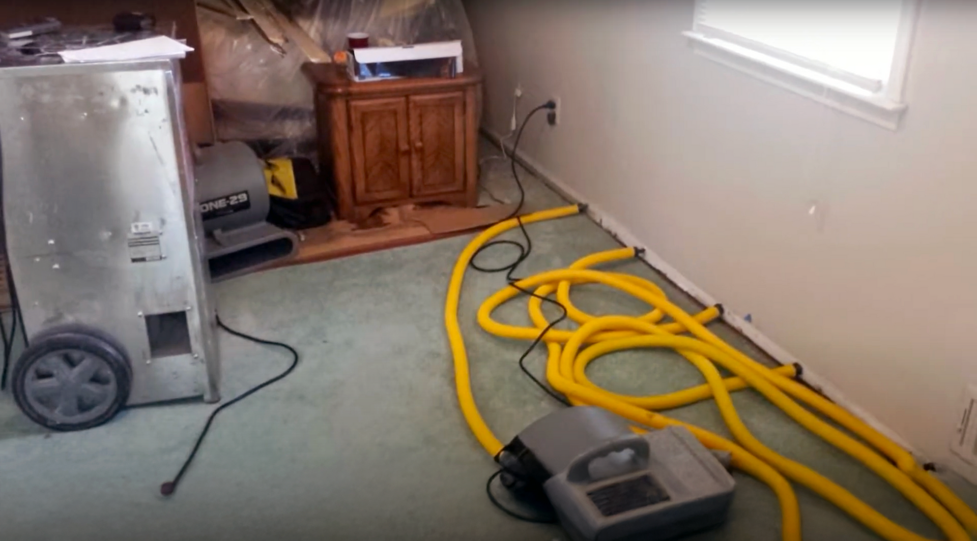 Water damage restoration flood cleanup in a Newport Beach home, using a desiccant dehumidifier and wall cavity dryers for water extraction.