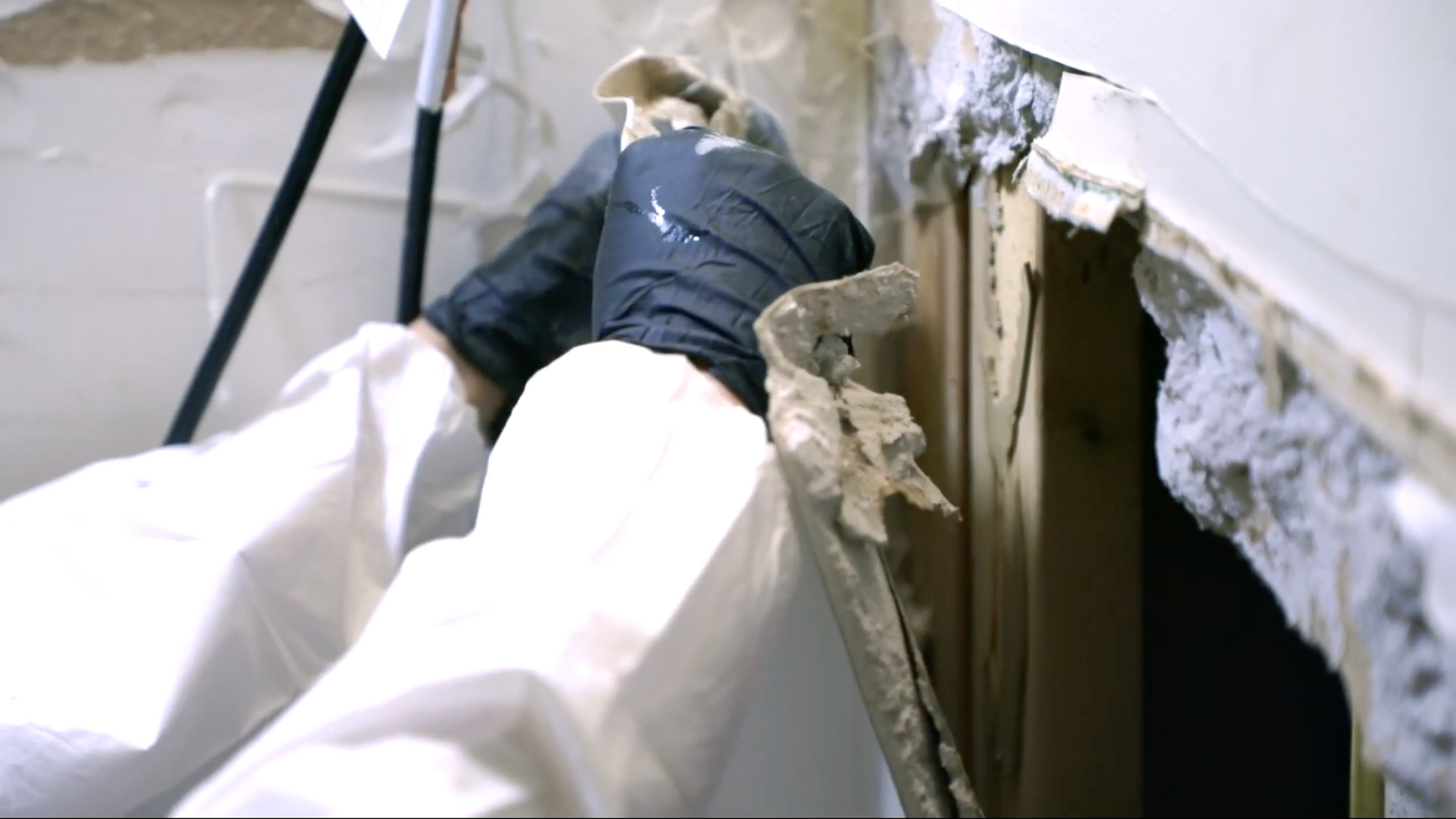 Restoration technician removing moldy drywall during water damage repair and mold remediation process.