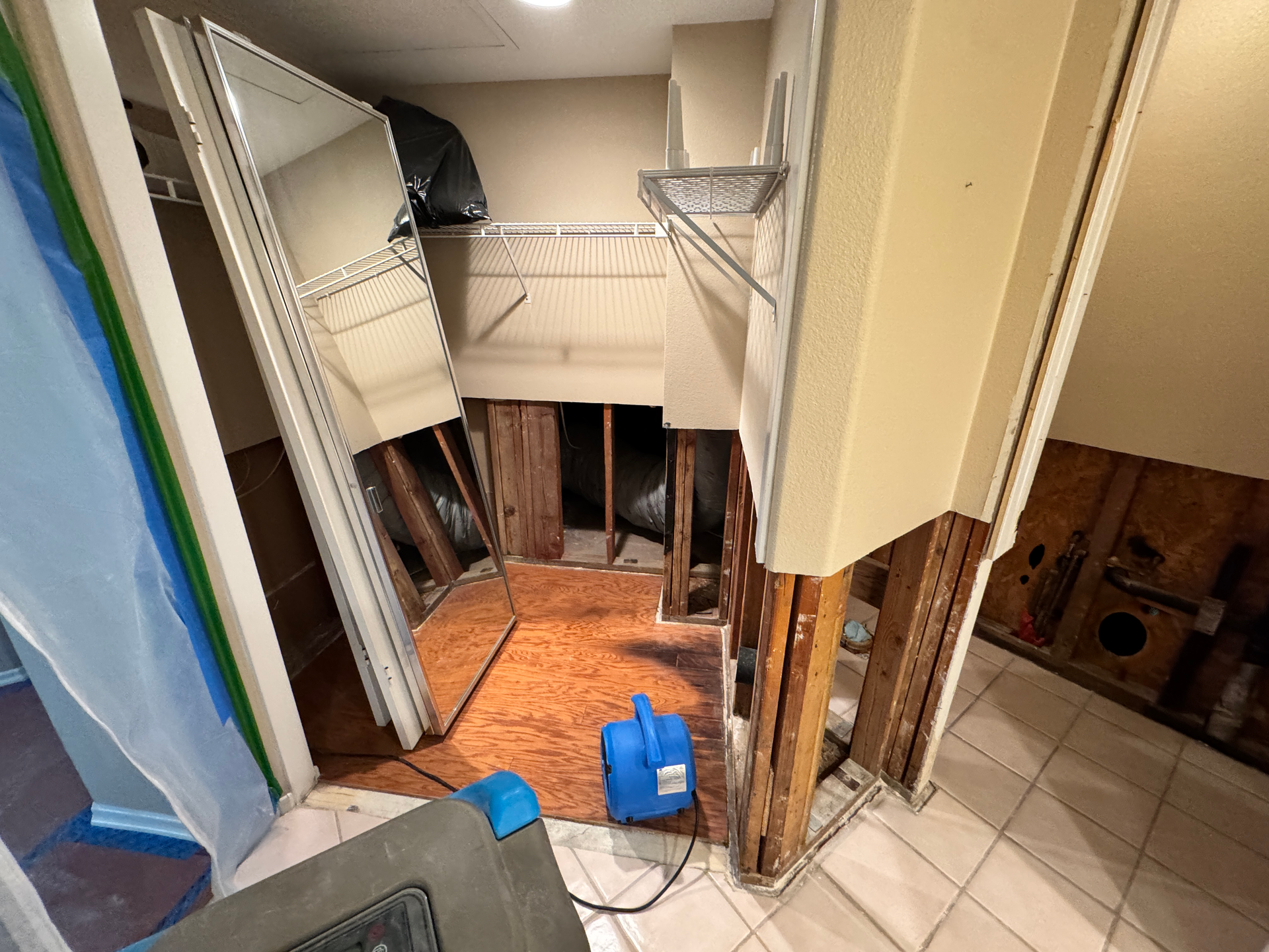 Before/after water damage: soaked floor and crumbling drywall vs. dried, rebuilt floor and finished wall — Pomona, California.