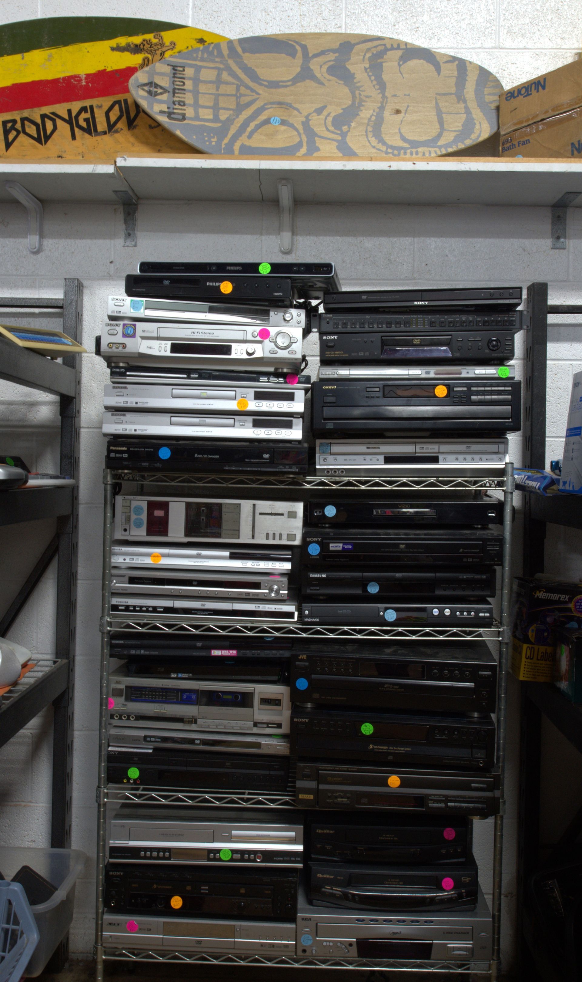 A bunch of dvd players are stacked on top of each other on a rack.