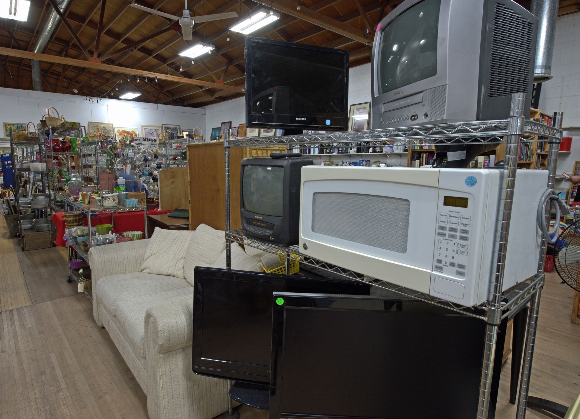 A store filled with lots of electronics including a microwave and televisions.