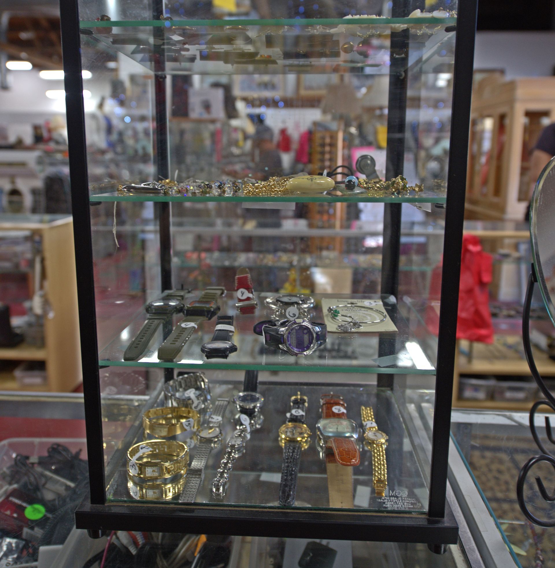 A glass display case filled with various items including watches