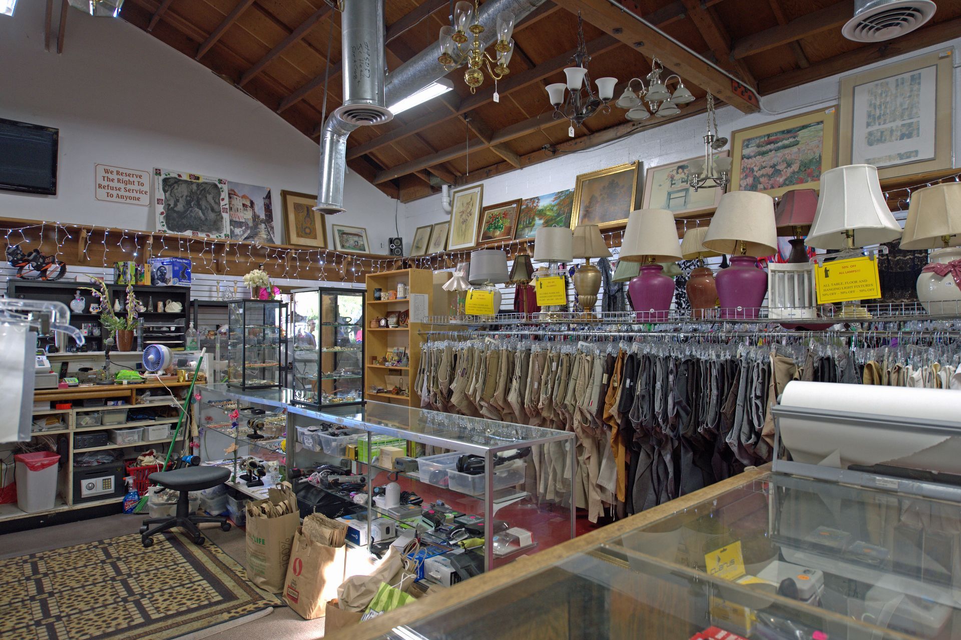 A store filled with lots of lamps and clothes hanging on racks.