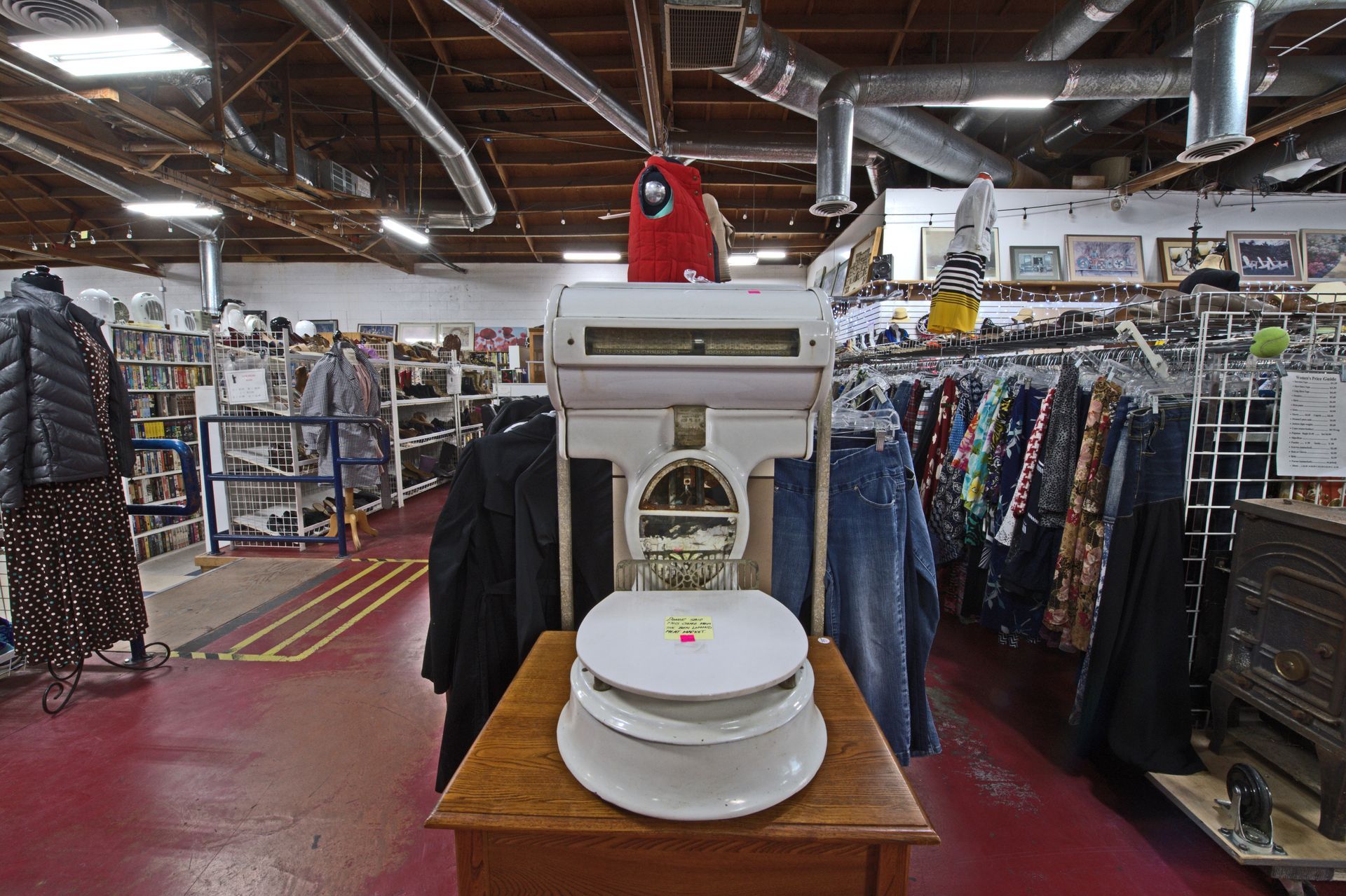 A white toilet seat is sitting on a wooden table in a thrift store.