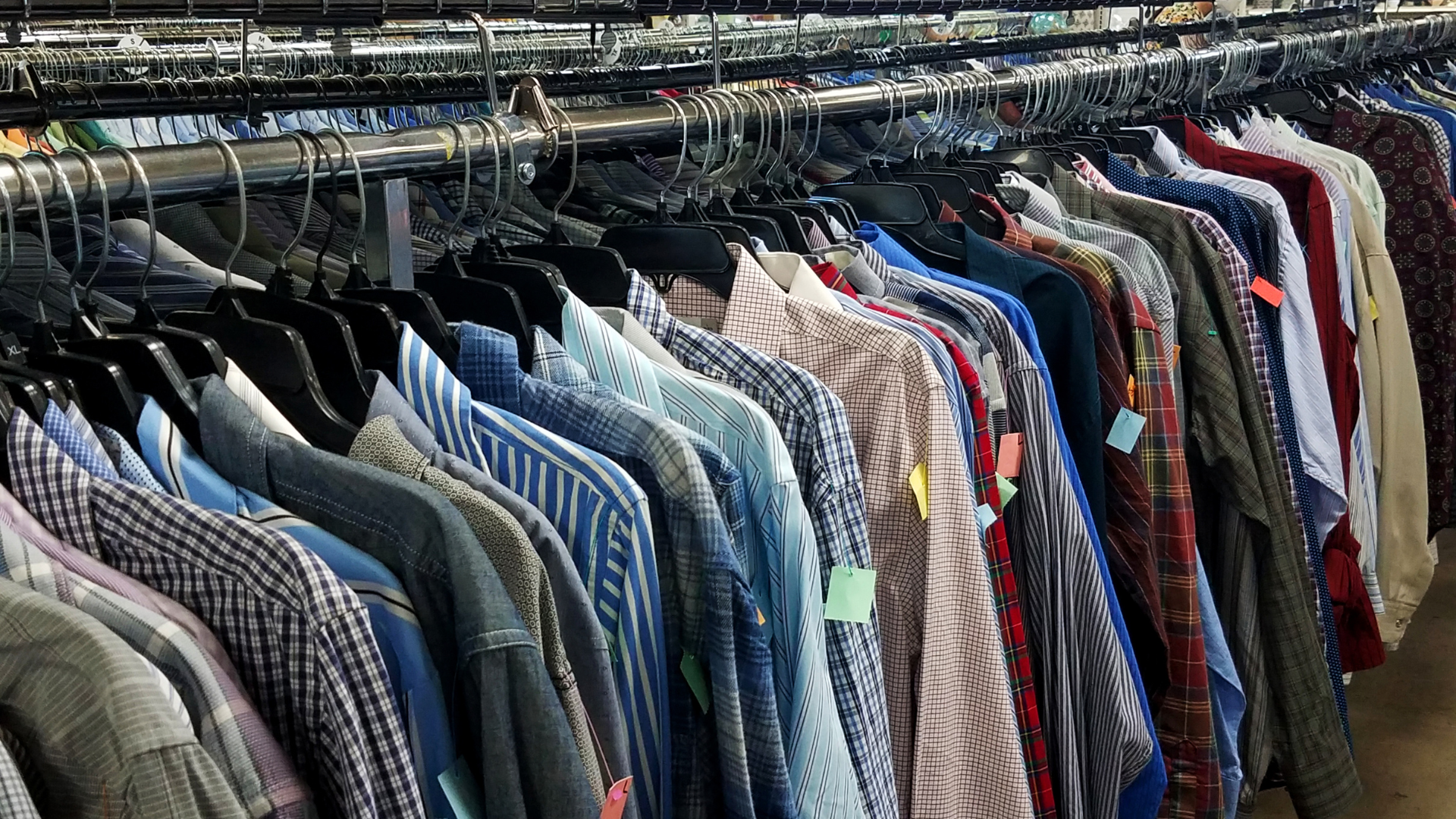 A row of shirts hanging on a rack in a store.