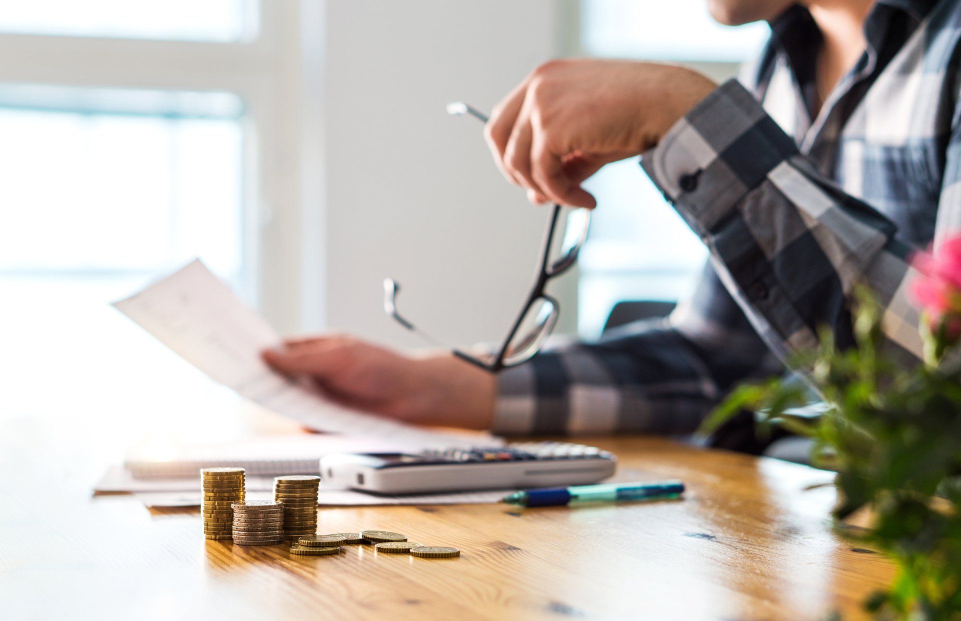 A man is sitting at a table with a calculator and coins.
