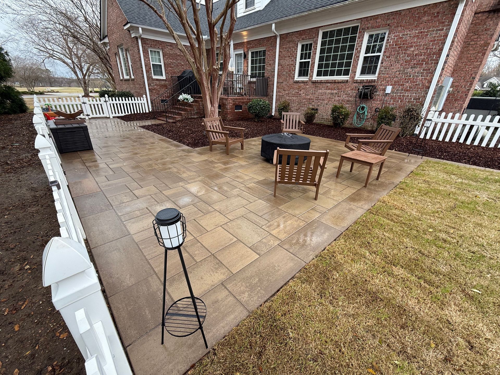 Brick home patio with seating, fire pit, and fence.
