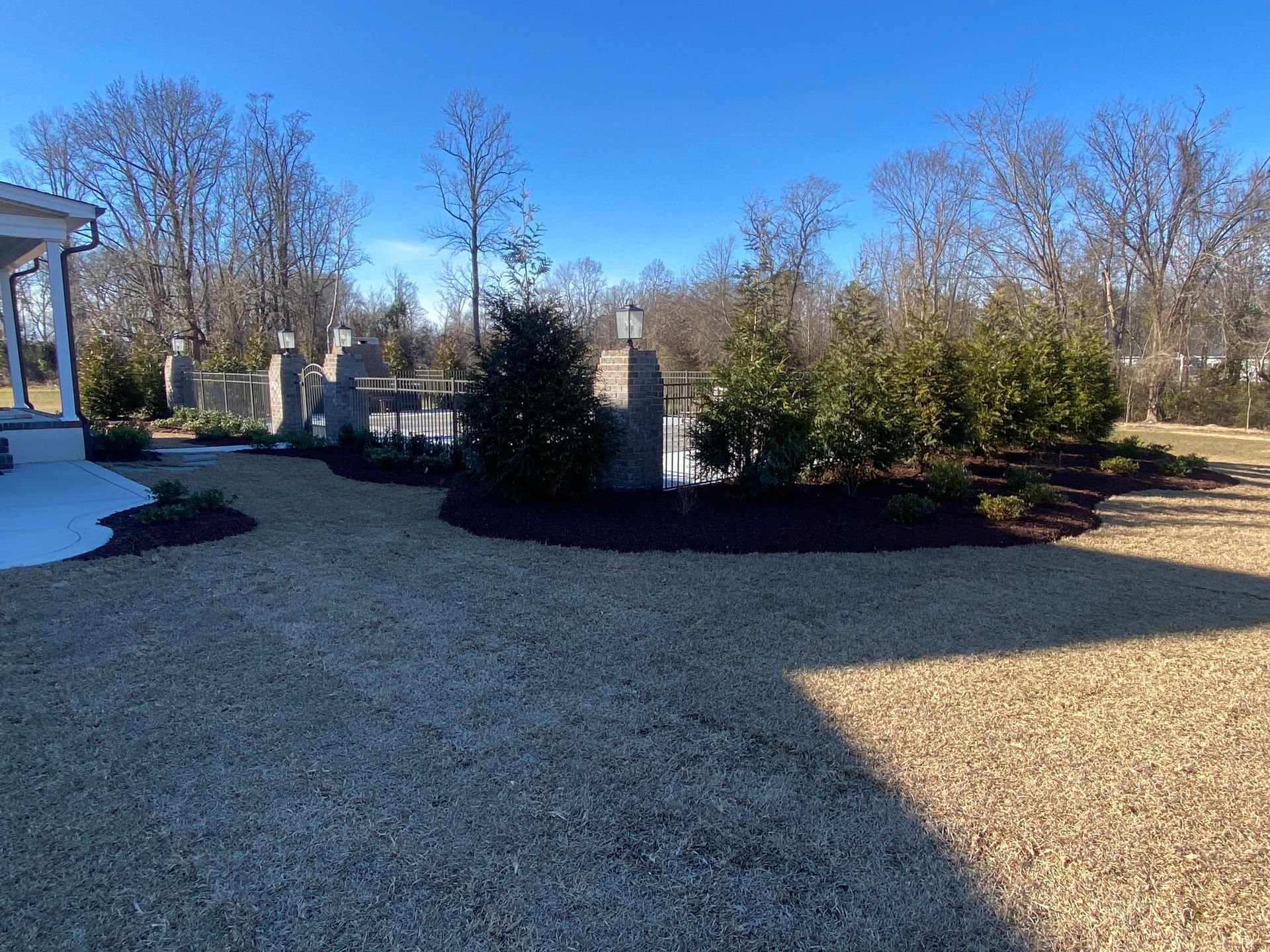 Lawn area with landscaping and a small bridge over water under a clear, sunny sky.