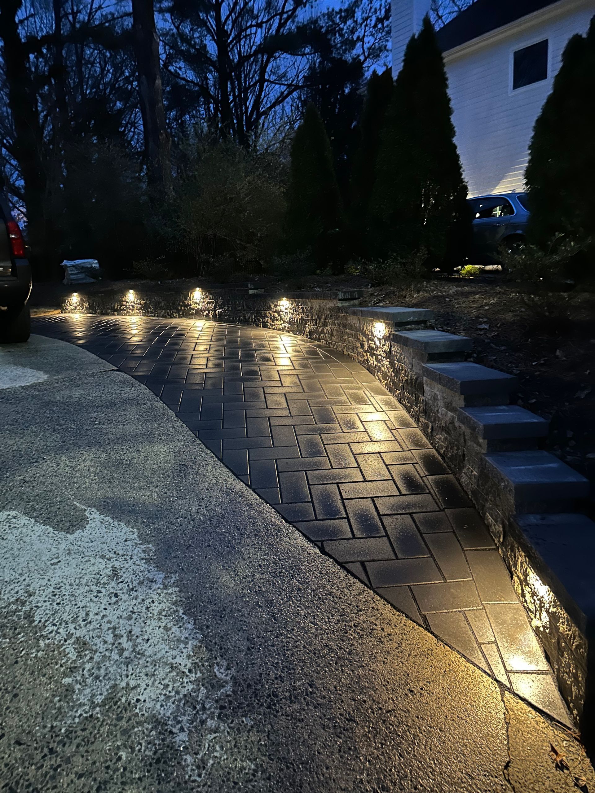 Lit brick path and steps at night with in-ground lights.