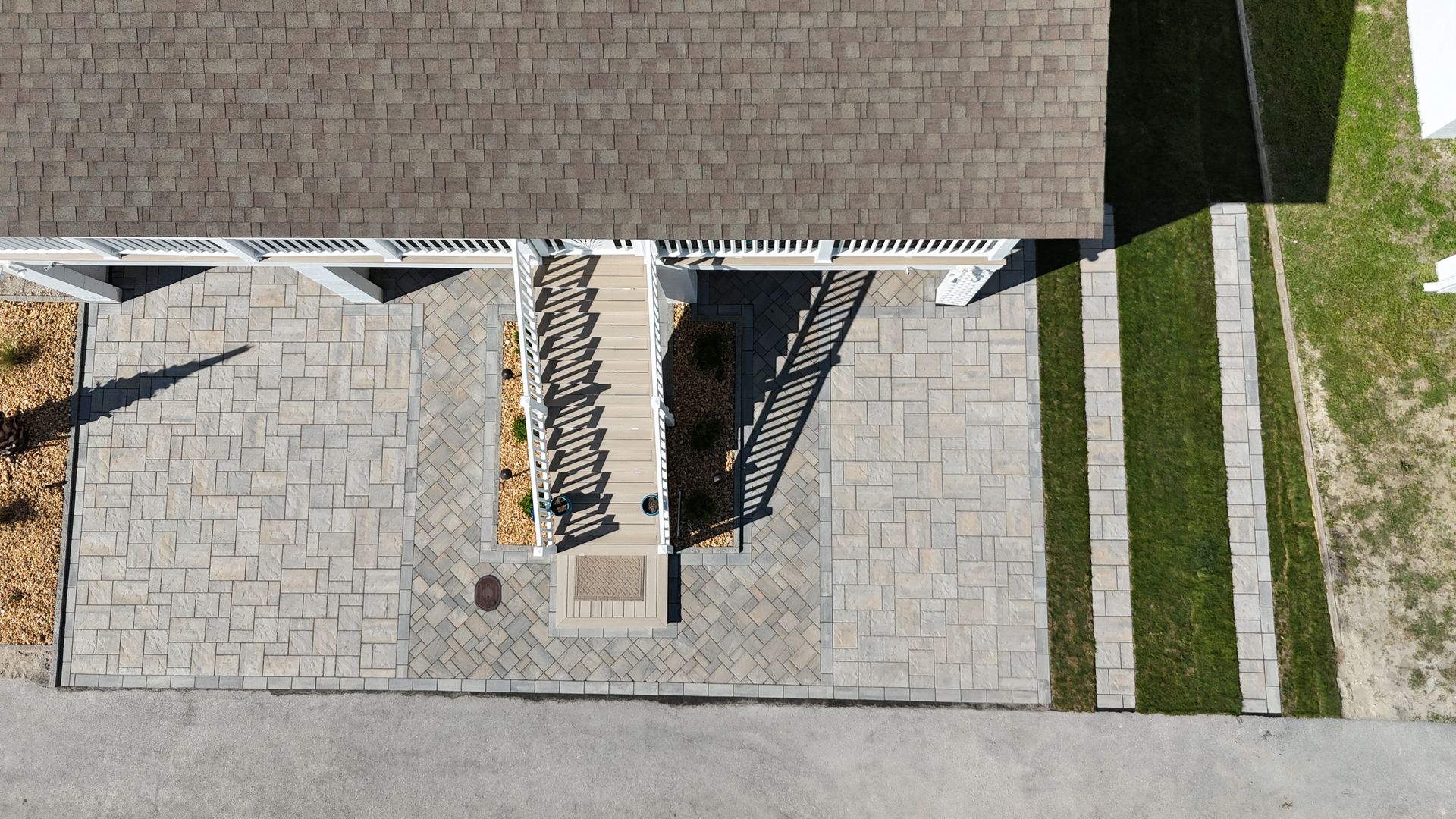 Overhead view of a house entrance with stone paving, stairs, and grass strips.