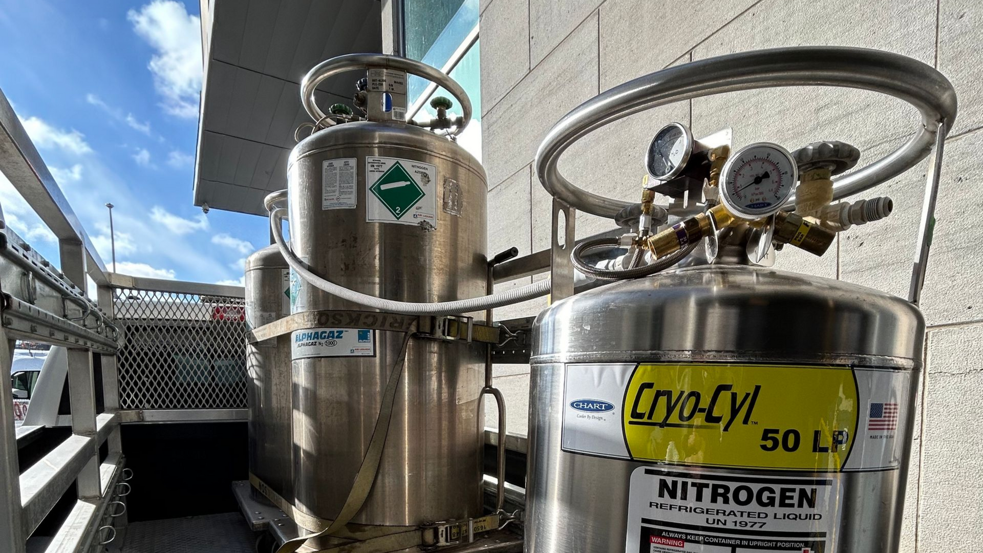 Several stainless steel nitrogen tanks outside, with gauges and safety labels.
