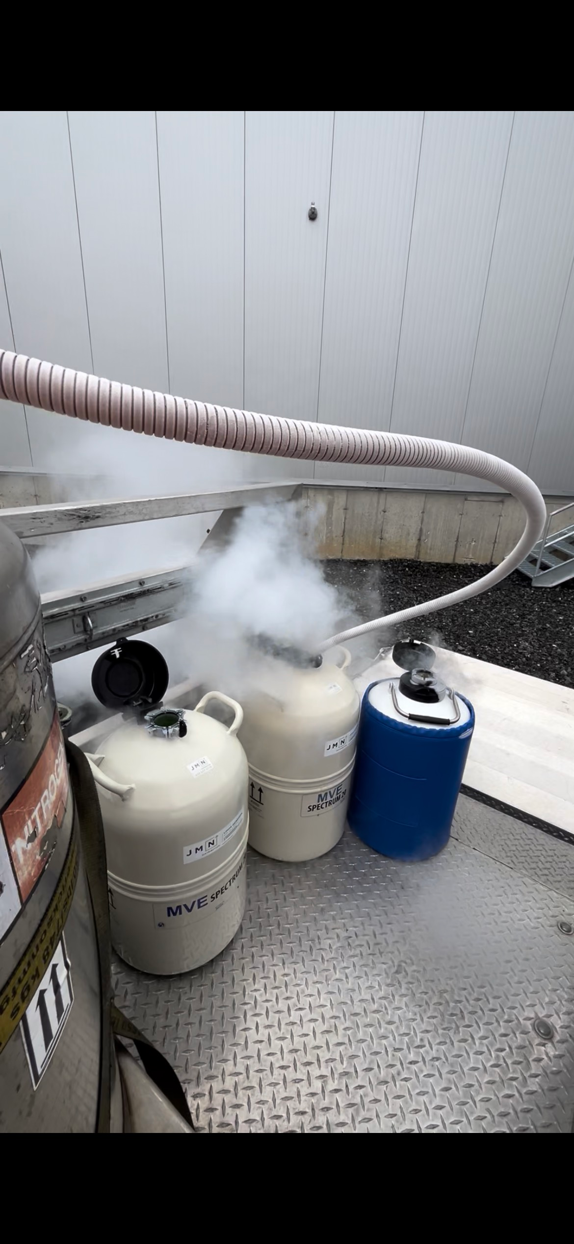 Three cryogenic liquid storage tanks, releasing vapor, on a metallic surface.