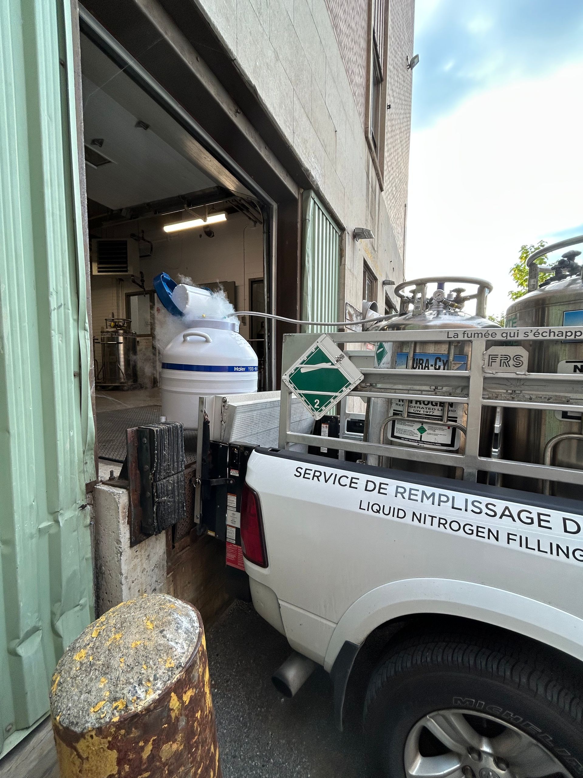 A white truck parked by a building, with gas tanks in the back.