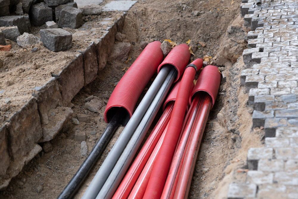 A Bunch of Red and Black Pipes Are Laying in the Dirt — Hardy's Excavations in Round Mountain, NSW