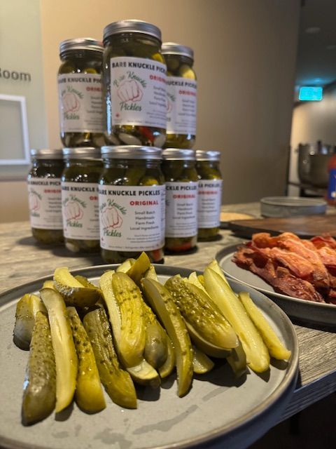 Jars of pickles stacked, with a plate of sliced pickles and deli meats.