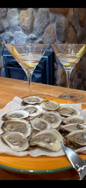 Oysters and martinis on a plate; a bar setting with a stone wall backdrop.