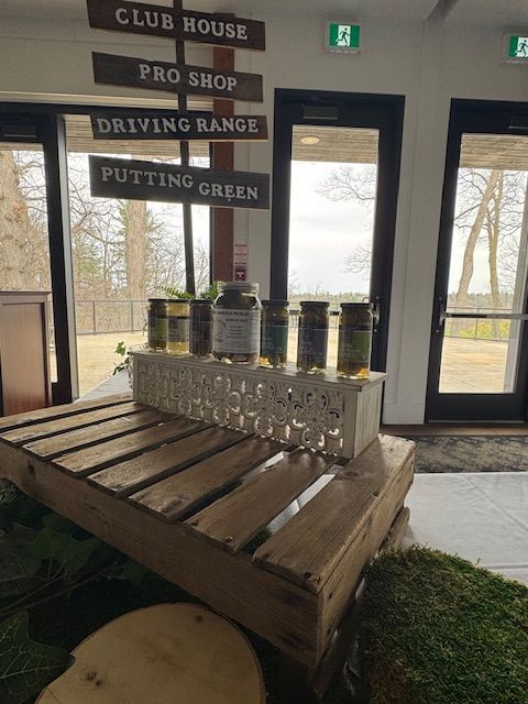 Golf course welcome display with signs, drinks, and pallet base near windows.