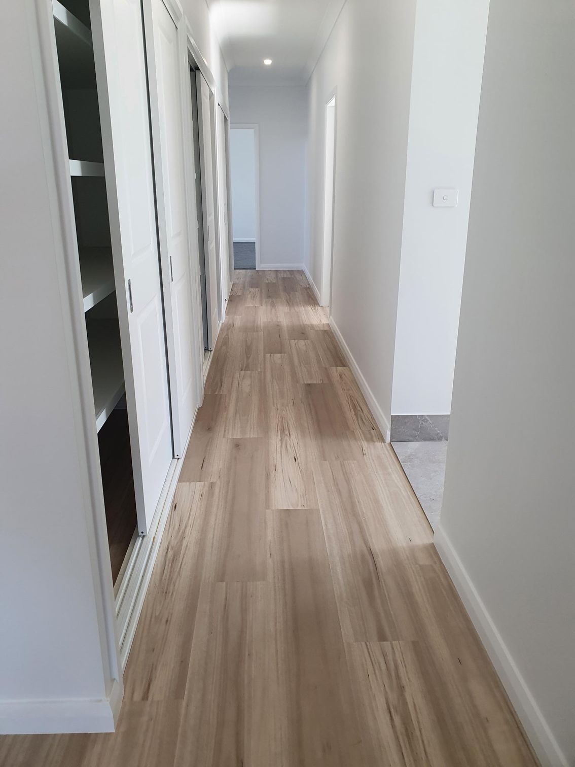A long hallway with vinyl plank floors and white walls.
