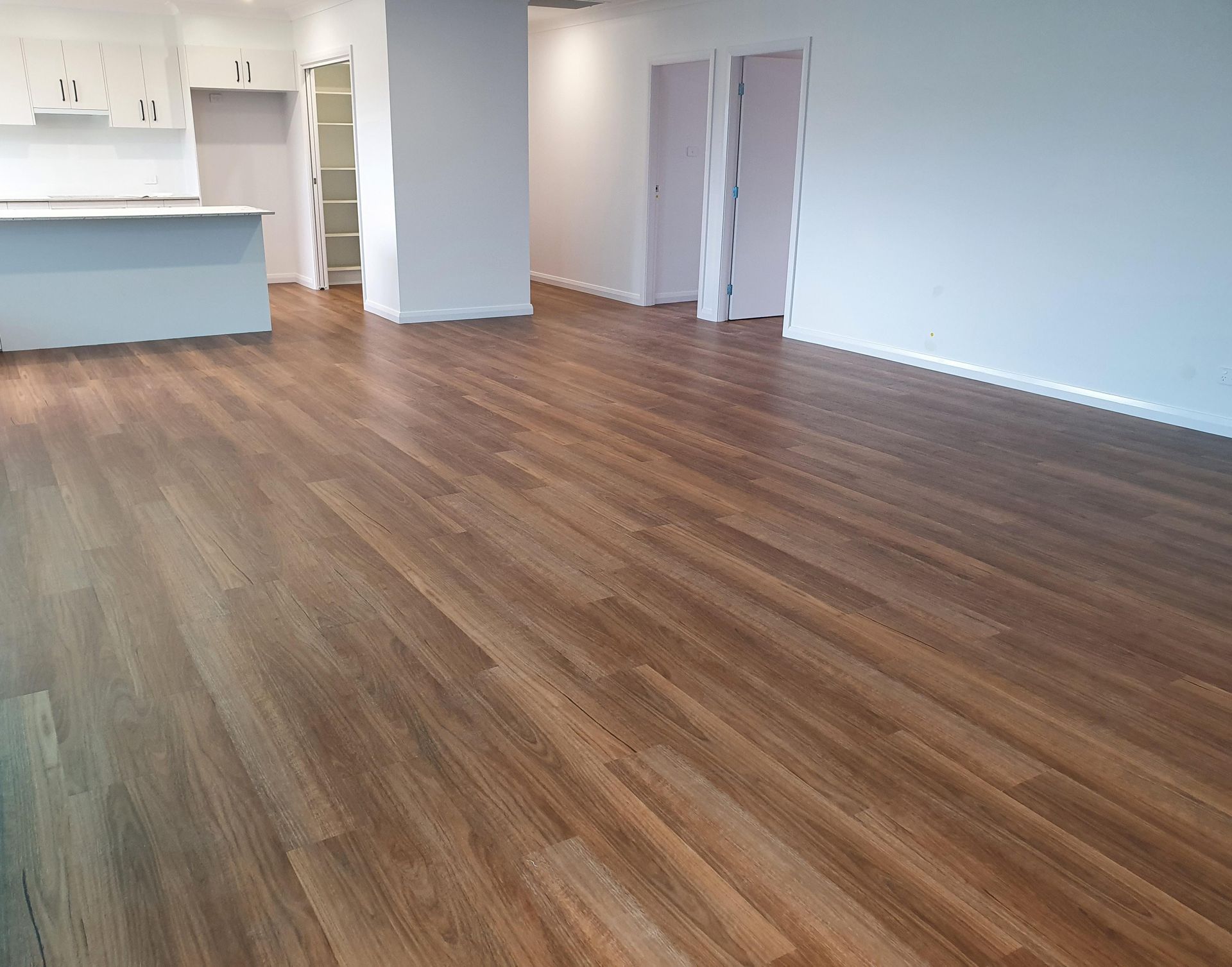 A large empty room with a vinyl floor and white walls.