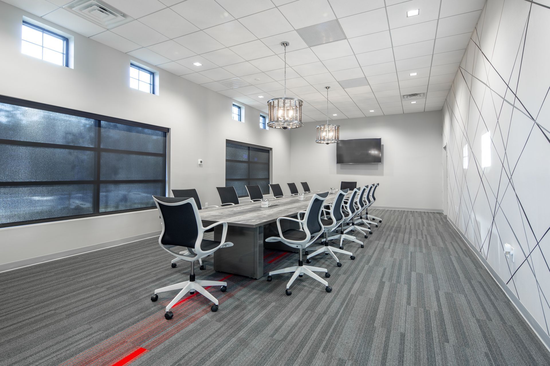 Modern conference room with long table, chairs, and TV on a patterned carpet.