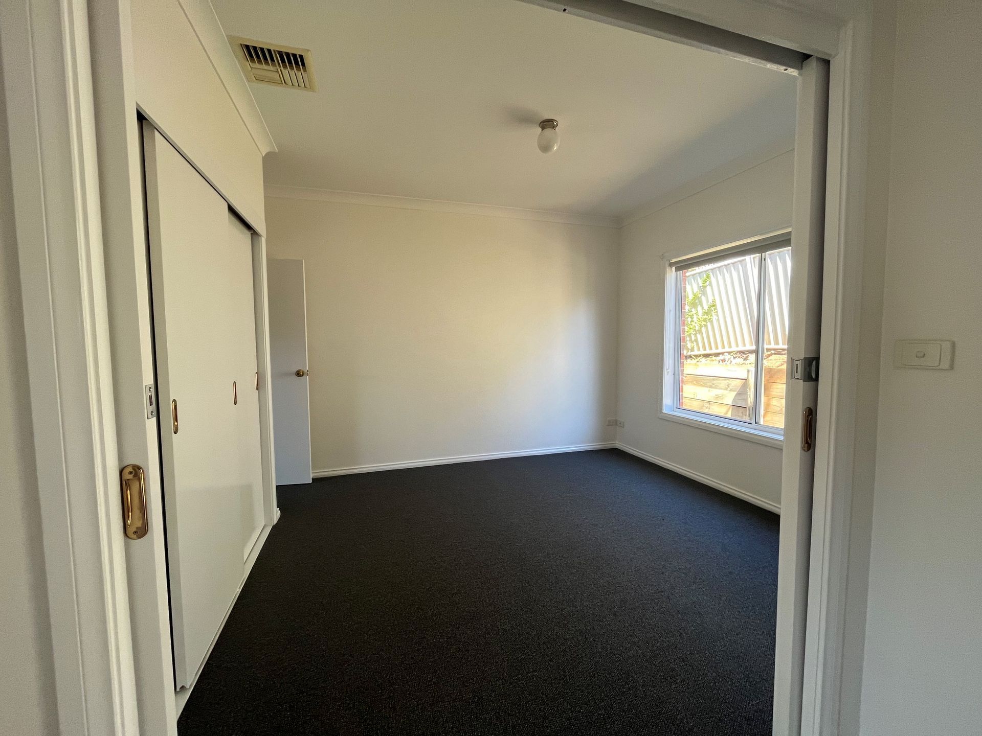An empty room with black carpet and white walls.