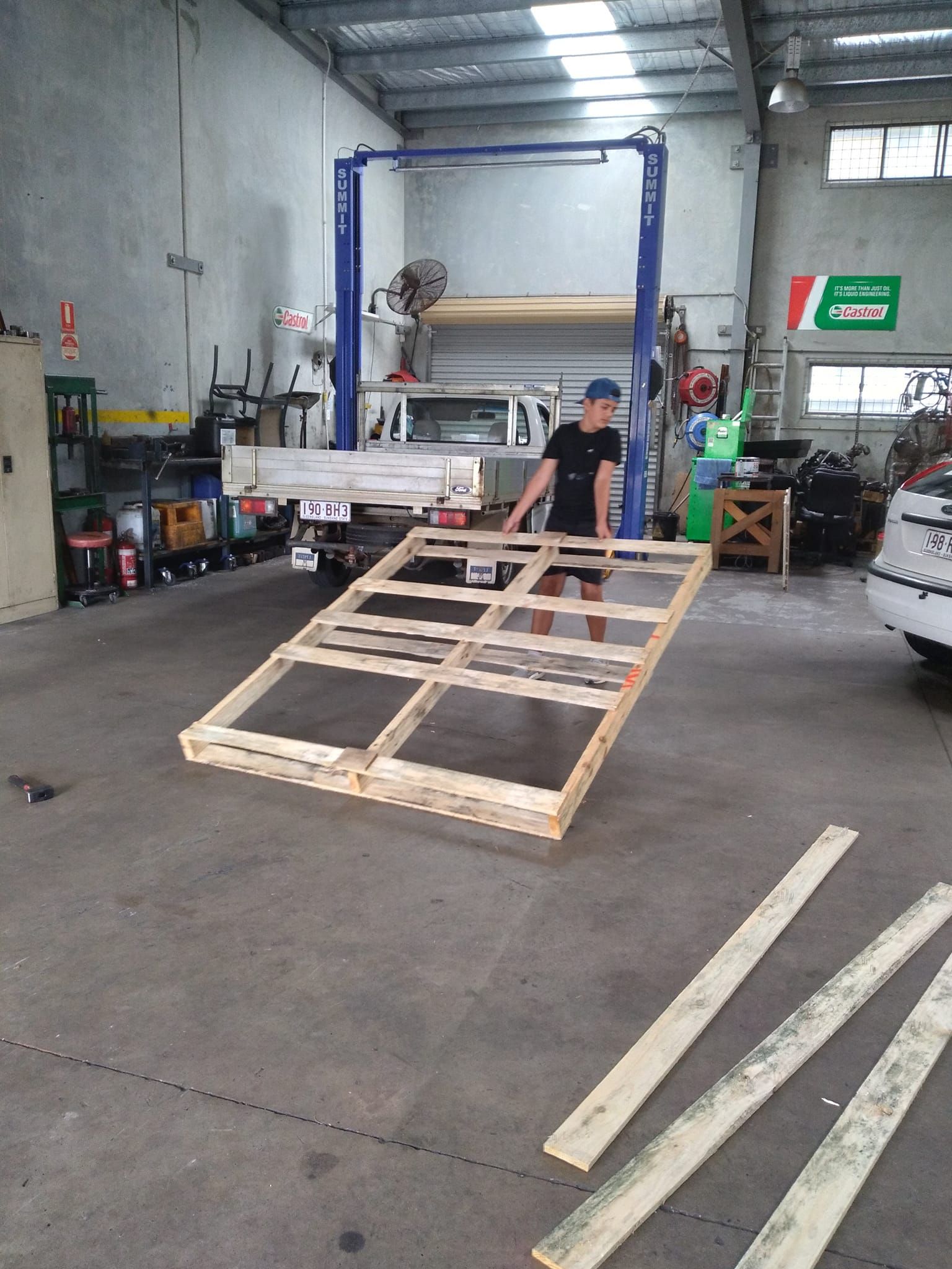 A Man Is Carrying A Large Wooden Crate In A Garage — Headland Auto Servicing & Air Conditioning In Alexandra Headland, QLD