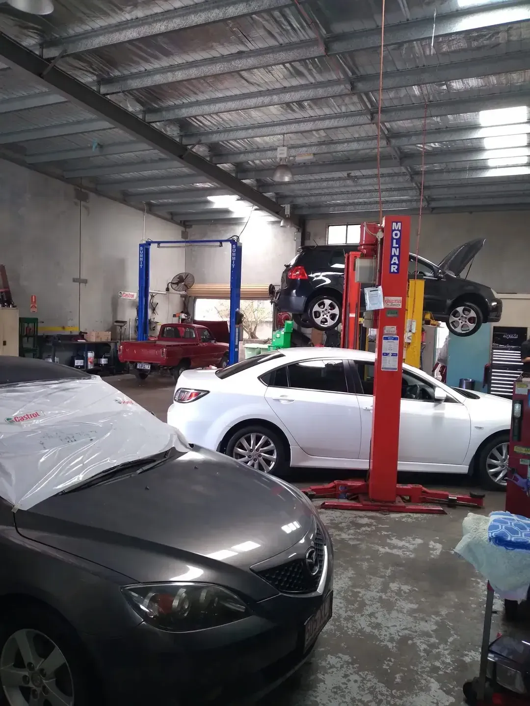 A Garage Filled With Cars And A Lift — Headland Auto Servicing & Air Conditioning In Alexandra Headland, QLD