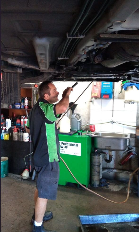 A Man Is Cleaning The Underside Of A Car — Headland Auto Servicing & Air Conditioning In Alexandra Headland, QLD