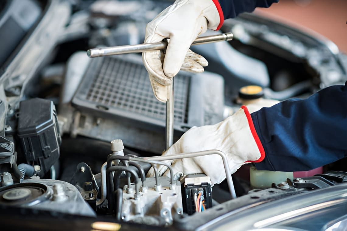 A Man Is Working On The Engine Of A Car With A Wrench — Headland Auto Servicing & Air Conditioning In Alexandra Headland, QLD