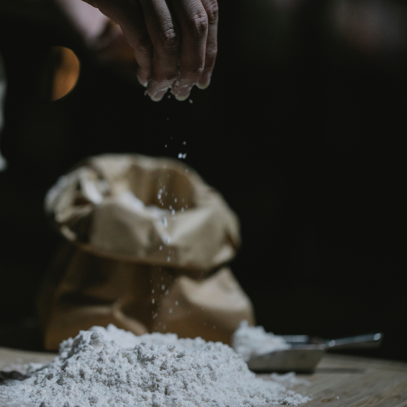 A person is pouring flour into a pile of flour