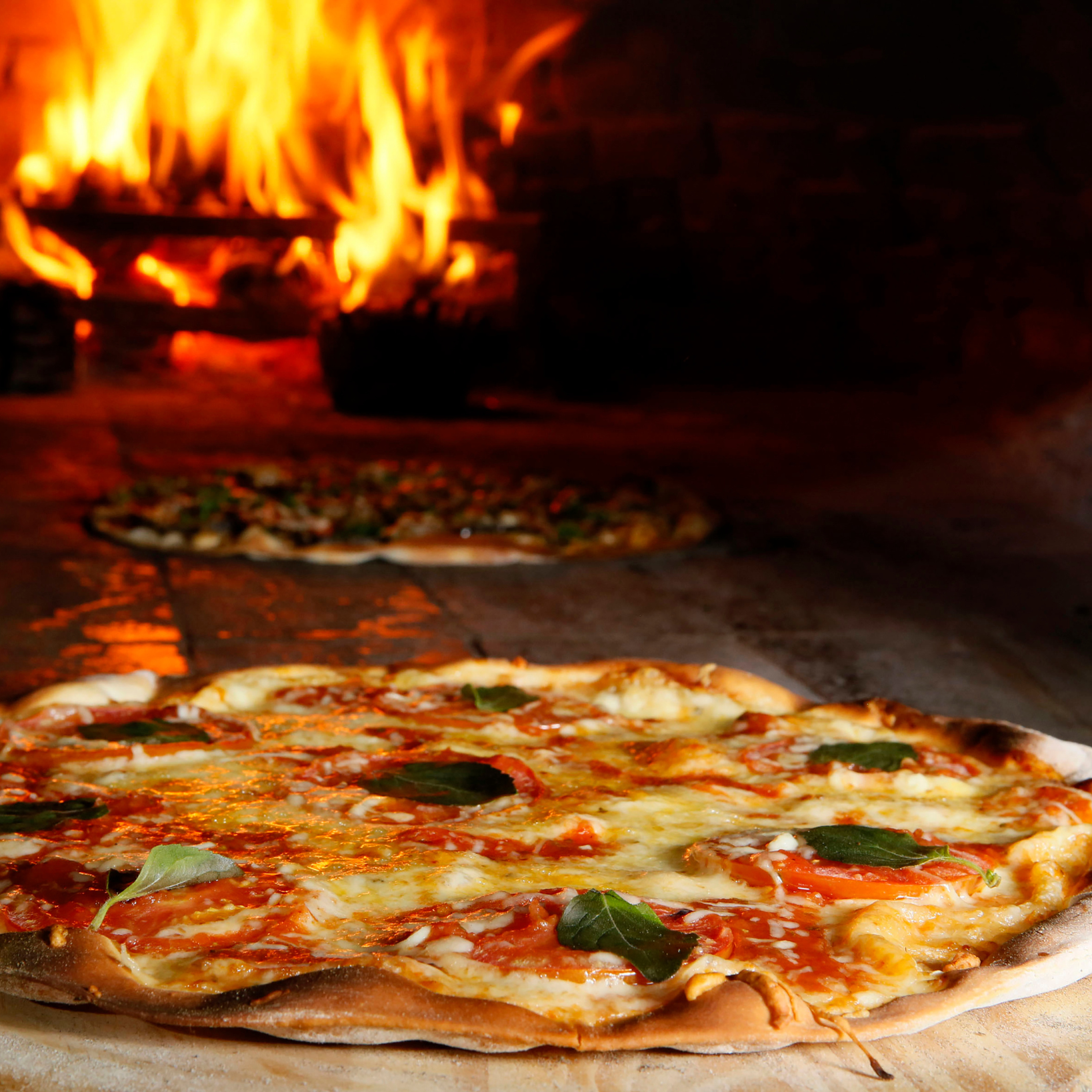 Bread baking on a carbon steel plate with flames in the background.