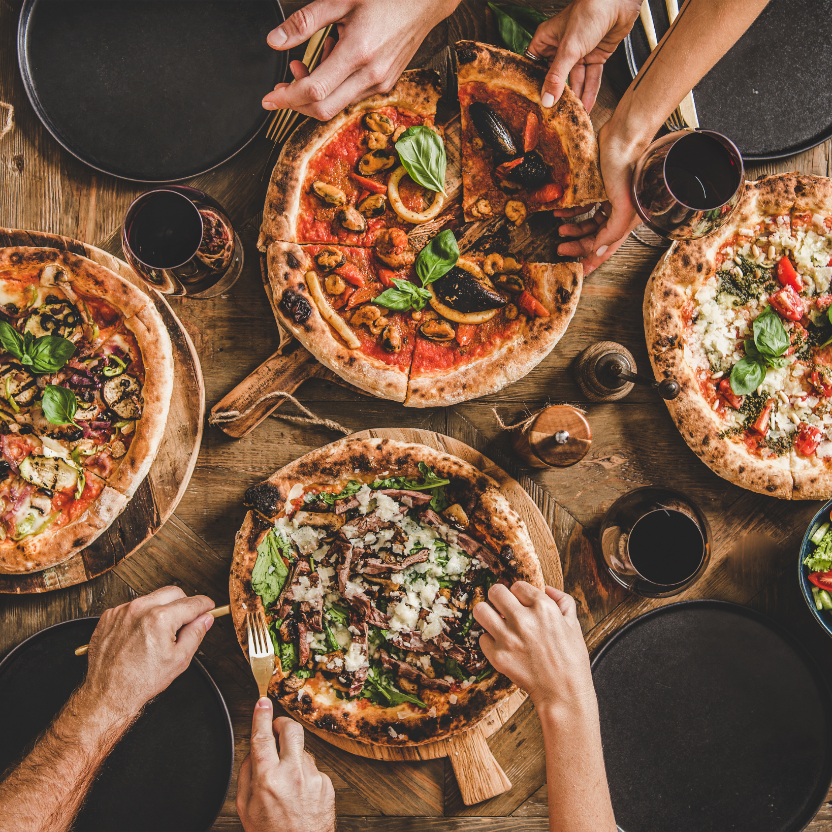 A group of people are sitting around a table eating pizza.