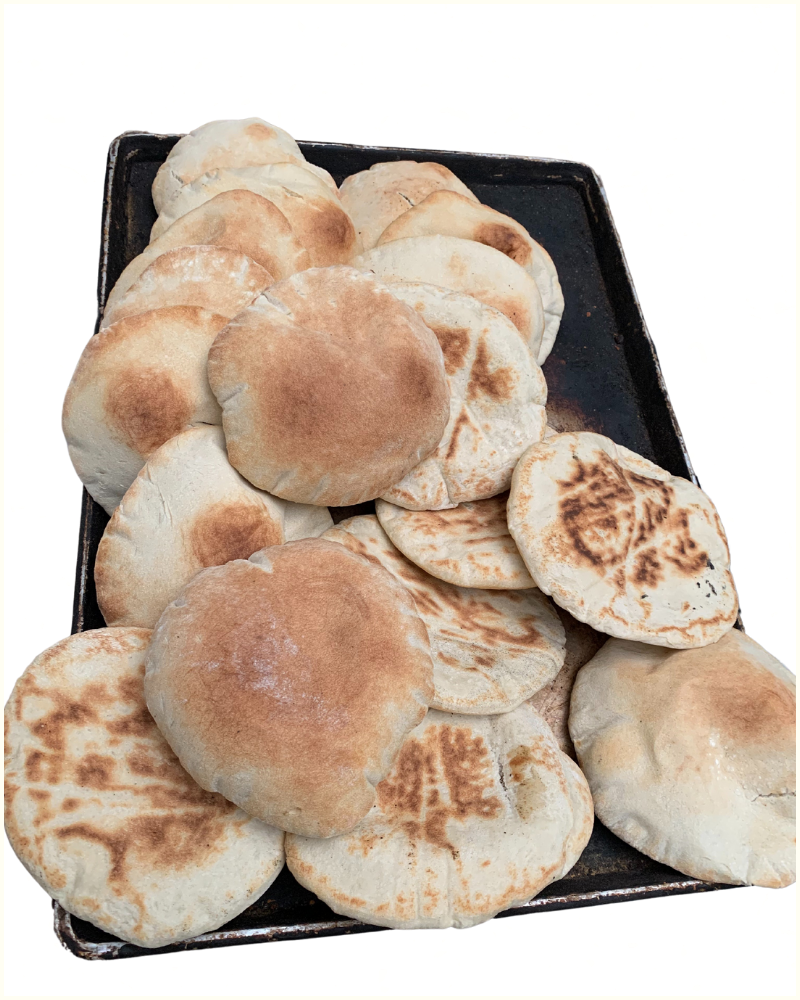 A pile of freshly baked pita flatbreads  on a black baking tray.