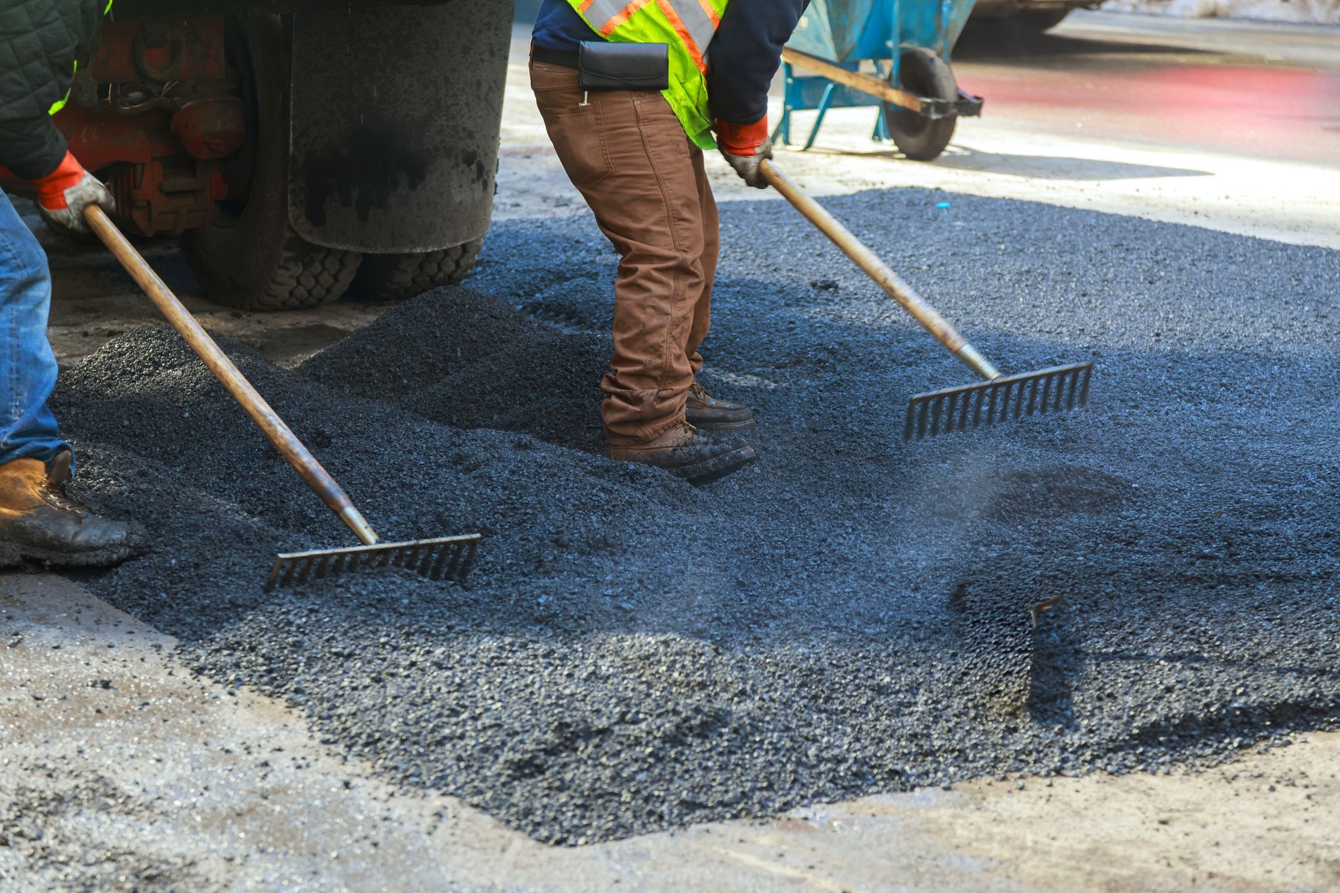 Workers raking fresh blacktop as part of professional commercial asphalt services on a parking lot. Workers raking fresh blacktop as part of professional commercial asphalt services on a parking lot.