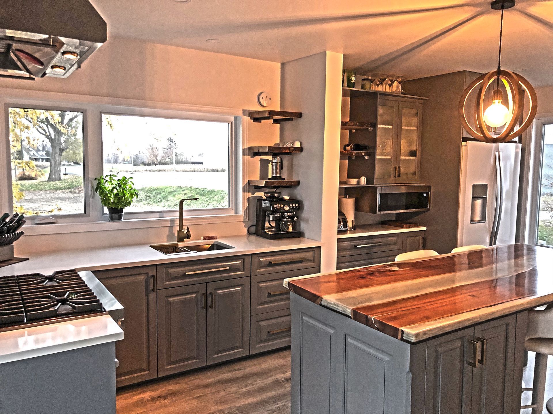 Cuisine moderne avec placards gris, plans de travail blancs et îlot central en bois.