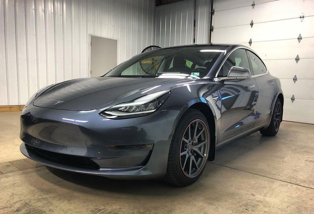 Gray Tesla Model 3 car parked inside a garage.