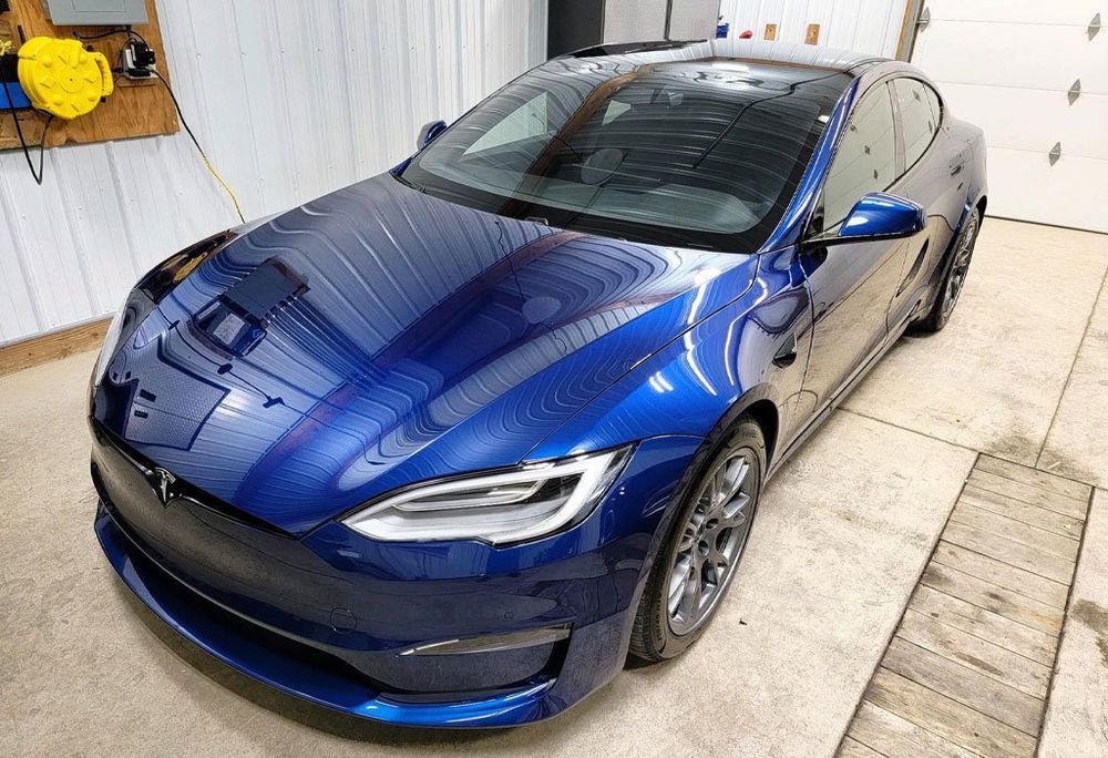 Blue Tesla sedan parked indoors.