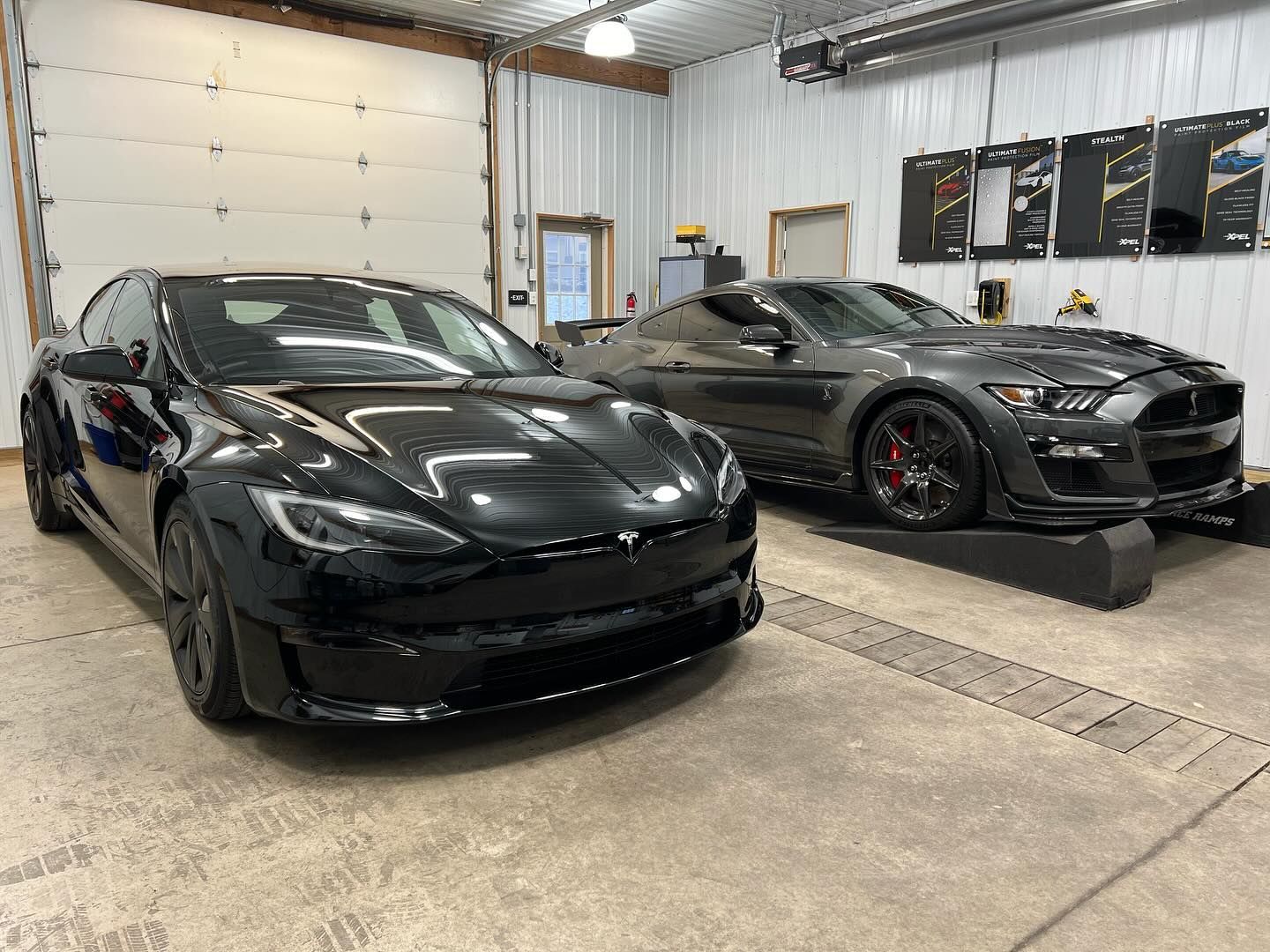 two black cars are parked next to each other in a garage .