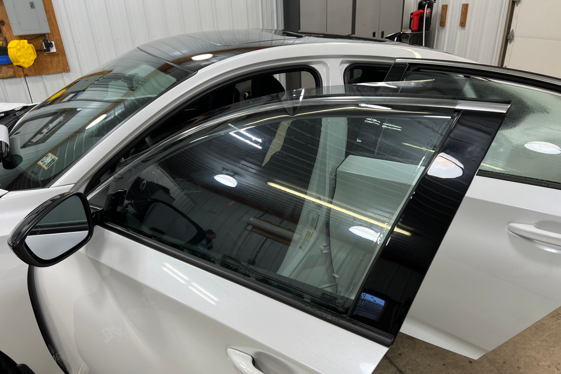 A man is applying tinted glass to a car window.