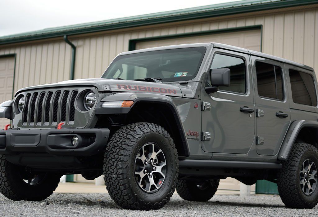 Gray Jeep Wrangler Rubicon SUV parked in front of a building.