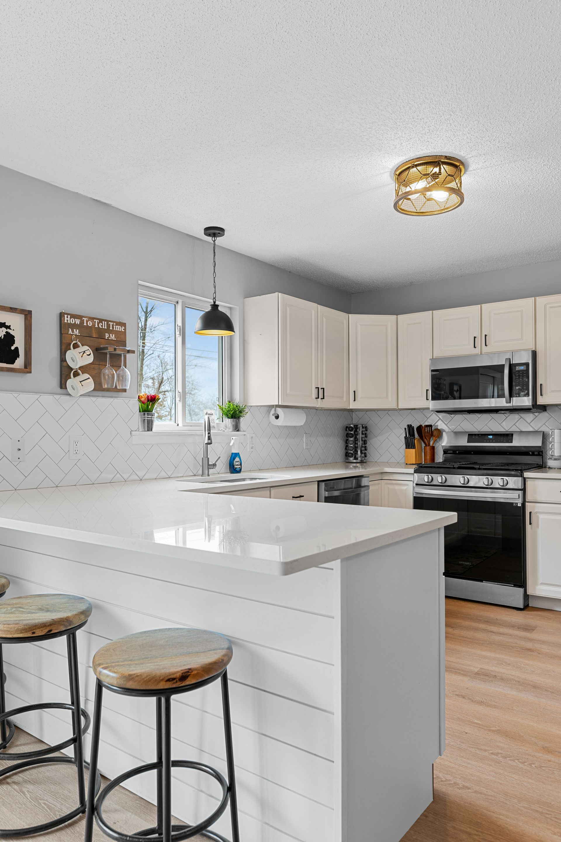 Modern kitchen with white cabinets, island, and stools, featuring a minimalist design.