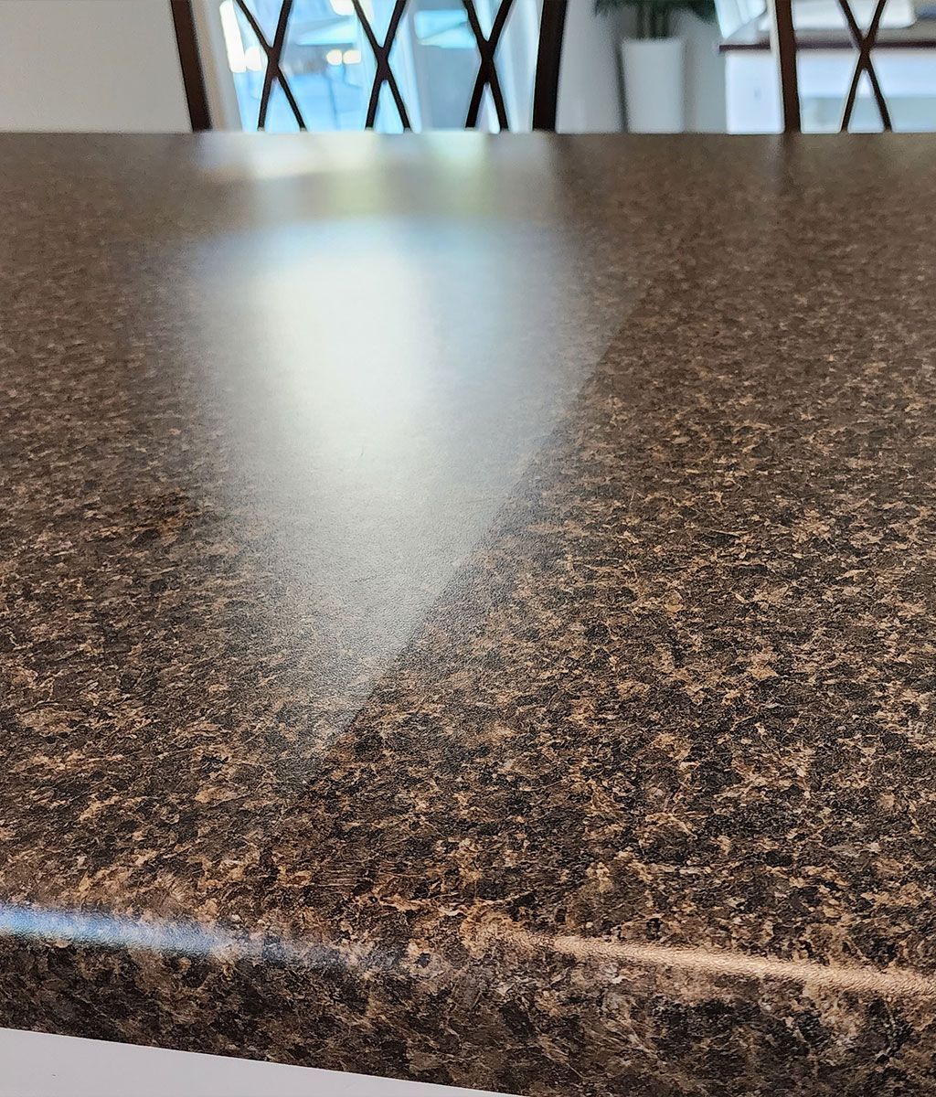 Brown speckled countertop reflects light with dining chairs in background.
