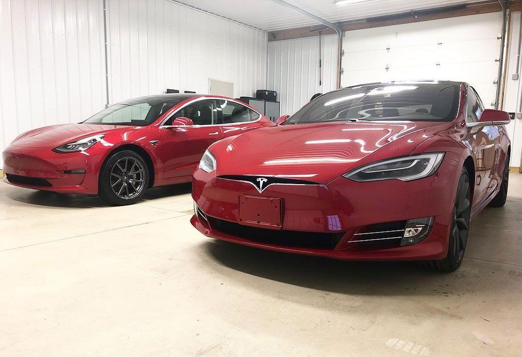Two red Tesla cars parked inside a garage.